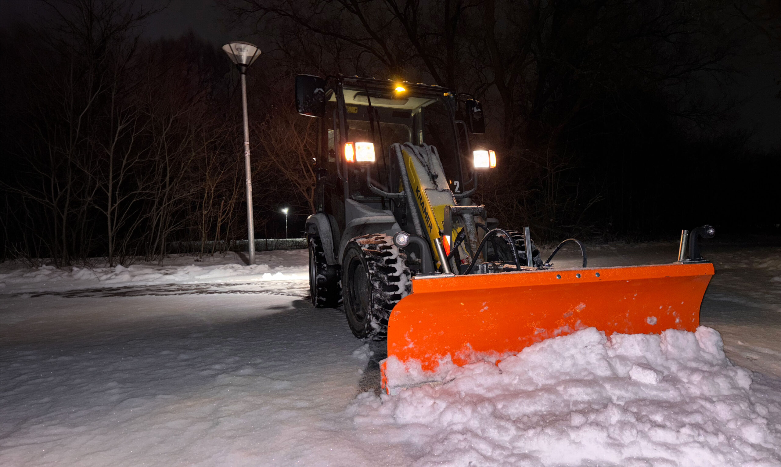Räumfahrzeug von VS Straßenbau bei nächtlichem Winterdienst-Einsatz auf verschneiter Straße